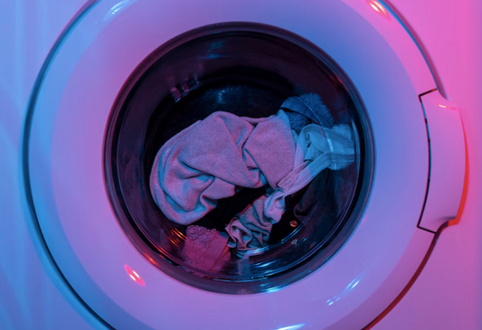 Laundry spinning in the dryer, lit by blue and pink lights