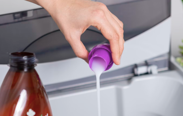 Laundry detergent being poured from the cap into the washing machine