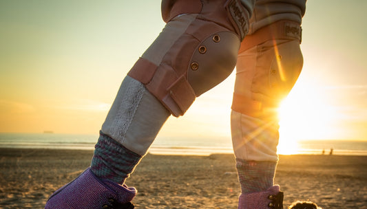 A person wearing knee pads and rollerblading on the beach.